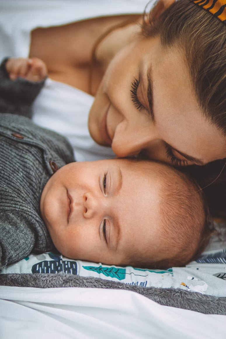 Moeder zit naast haar slapende pasgeboren baby