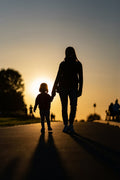 Moeder en kind hand in hand bij zonsondergang
