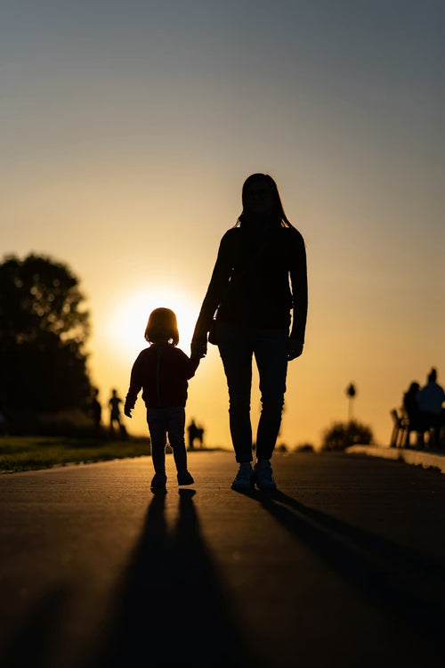 Moeder en kind hand in hand bij zonsondergang
