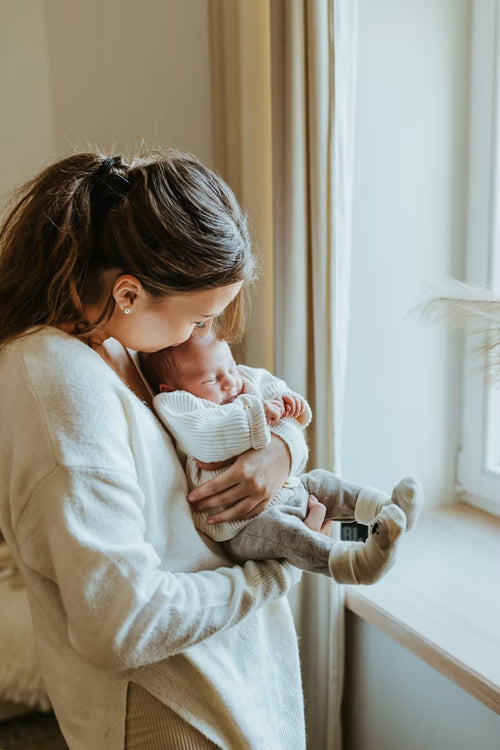 Moeder houdt pasgeboren baby vast bij het raam